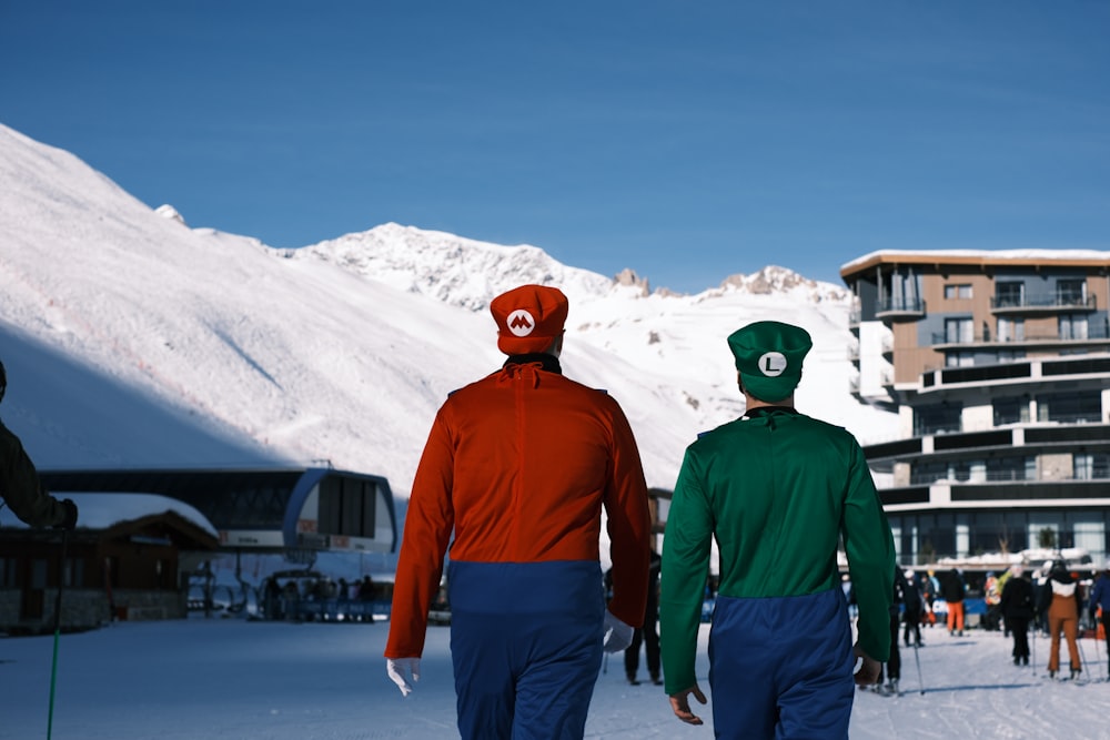 a couple of men walking across a snow covered slope