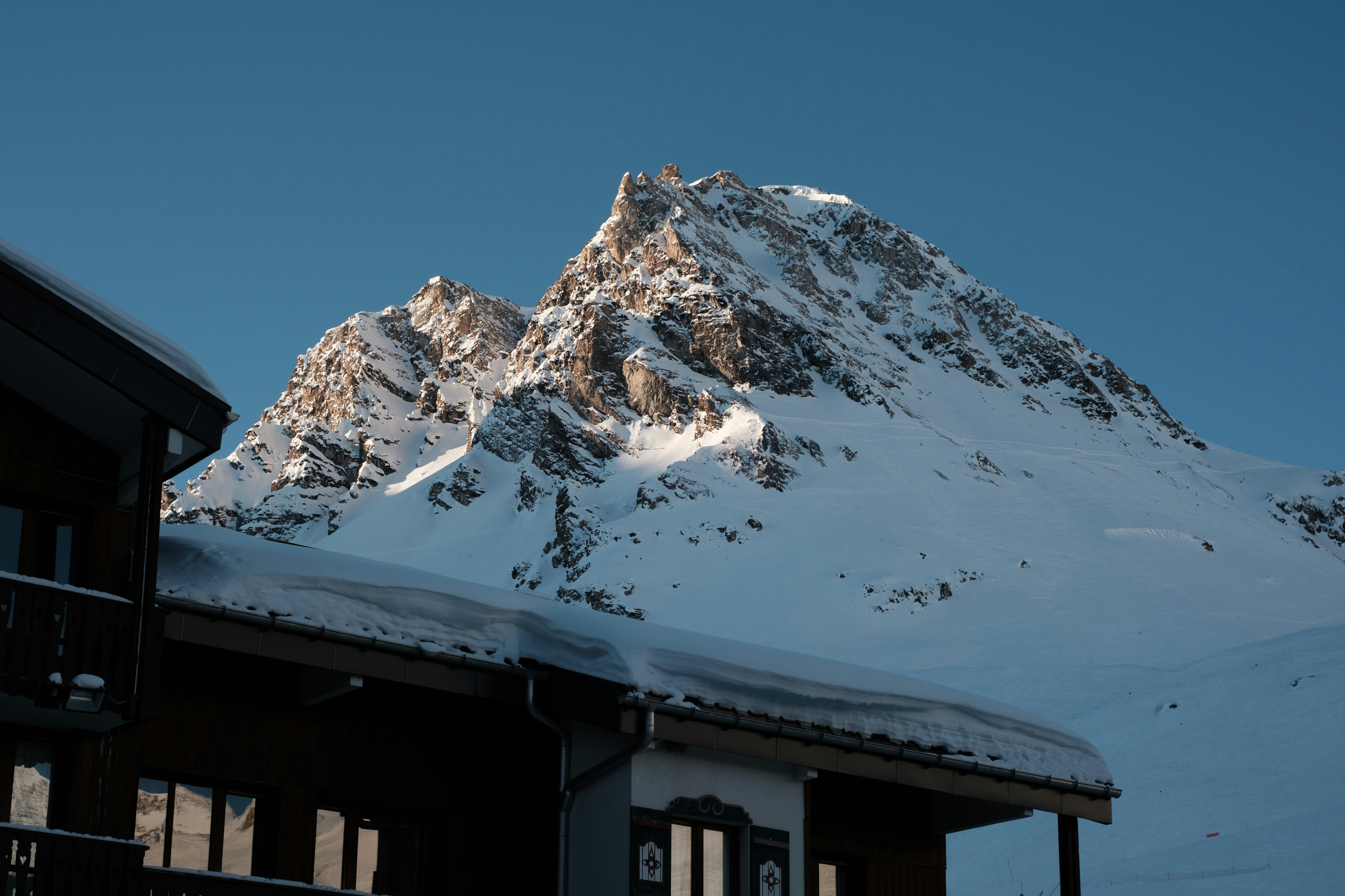 Una montagna innevata è sullo sfondo di un edificio