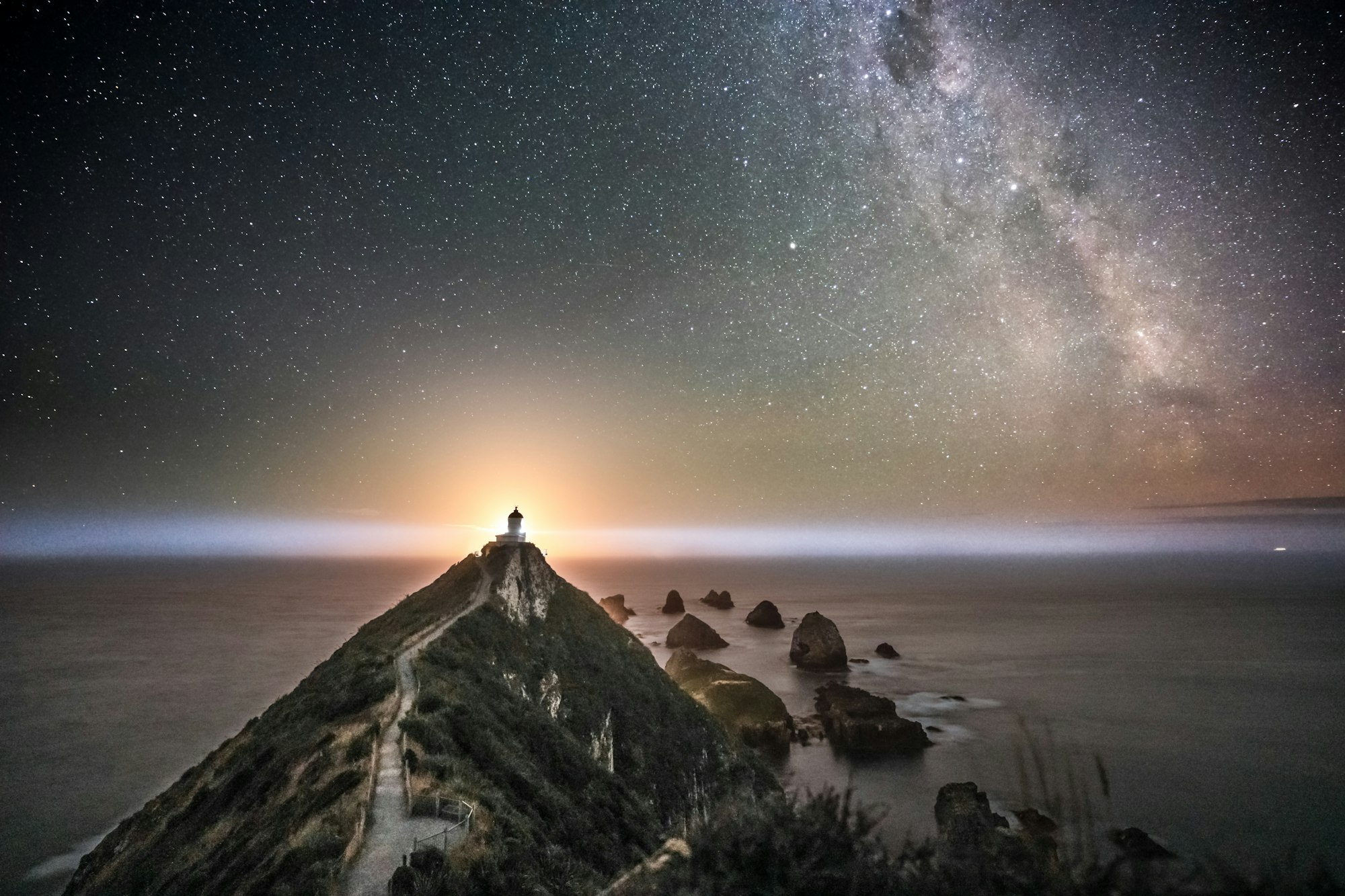 Nugget Point, New Zealand. A lovely image of a fantastic place with a perfect setting. One can see parts of the Milky Way and the moon rising perfectly aligned behind the lighthouse.