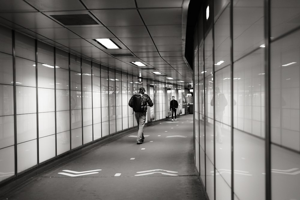 a man walking down a hallway next to a wall