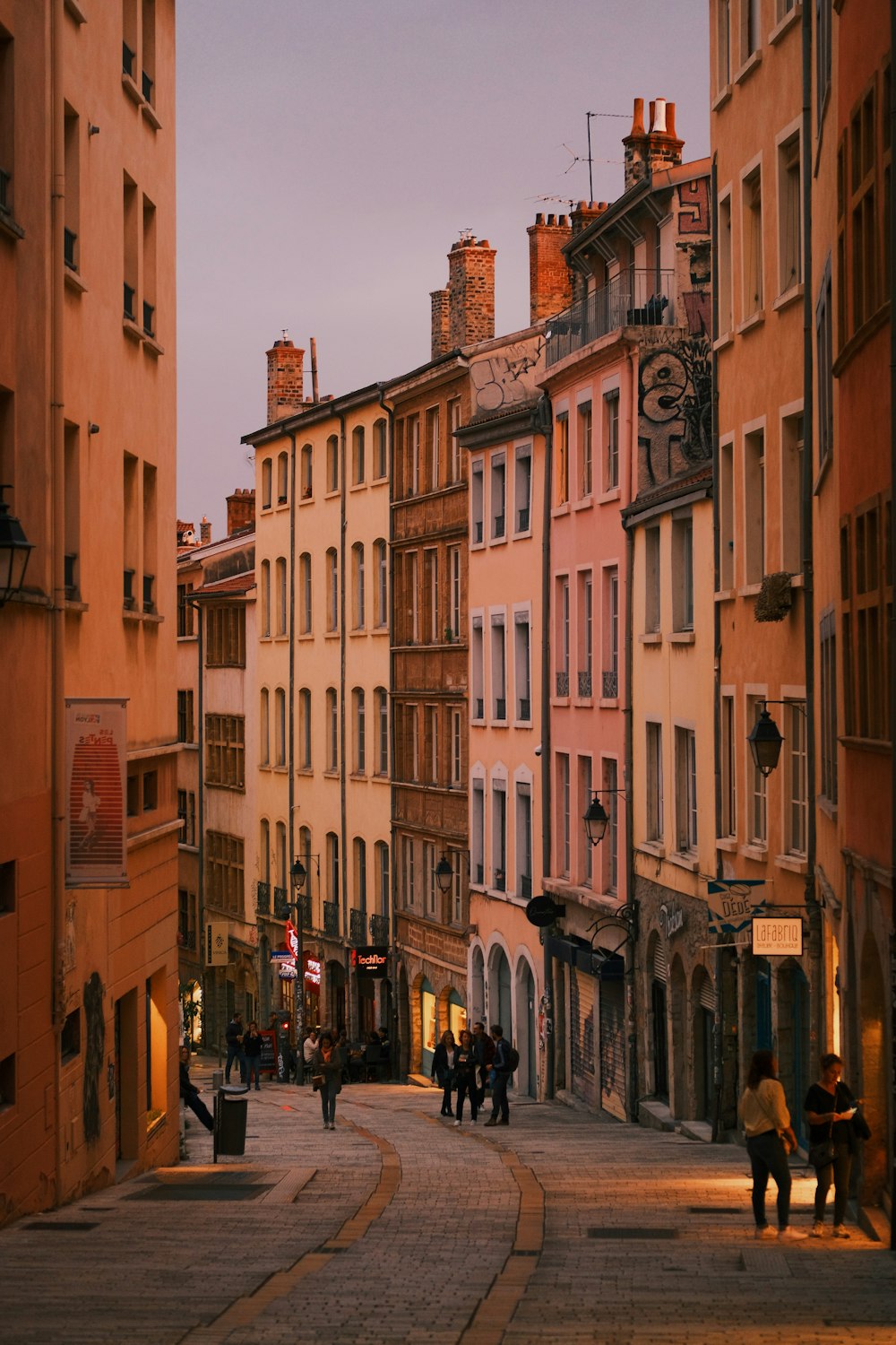 a group of people walking down a street next to tall buildings