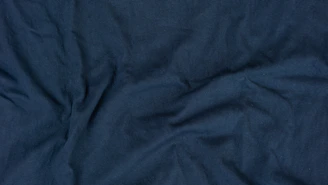 Navy blue women's suit shirt neatly folded with subtle shadows highlighting fabric texture
