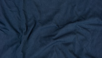 Folded navy blue fabric with visible fine stitching details highlighting premium quality.