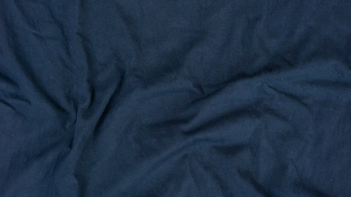 Navy blue women's suit shirt neatly folded with subtle shadows highlighting fabric texture