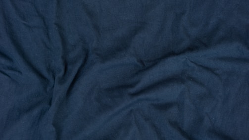 Folded navy blue fabric with visible fine stitching details highlighting premium quality.
