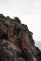A dramatic scene of a lone figure standing on a cliff edge under a stormy sky, emphasizing mood and scale.