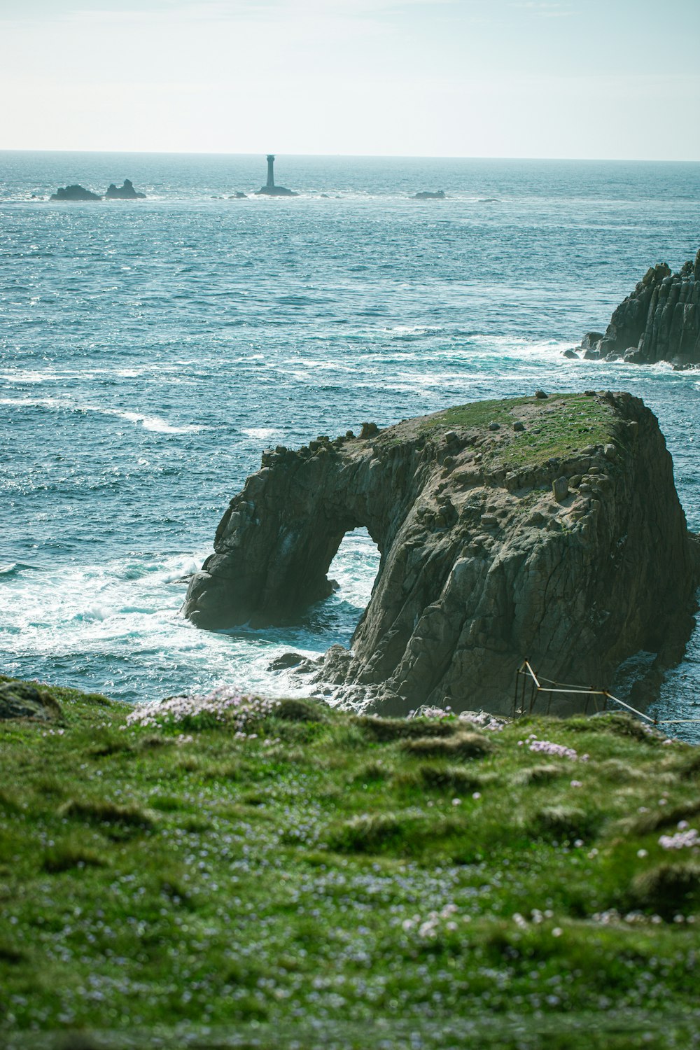 a rocky outcropping with a lighthouse in the distance