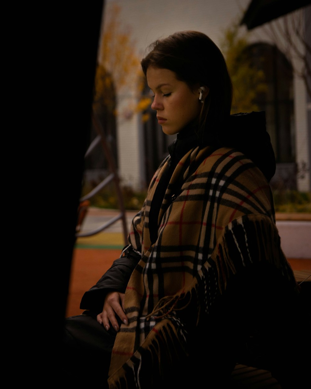 a woman sitting on a bench wearing a blanket