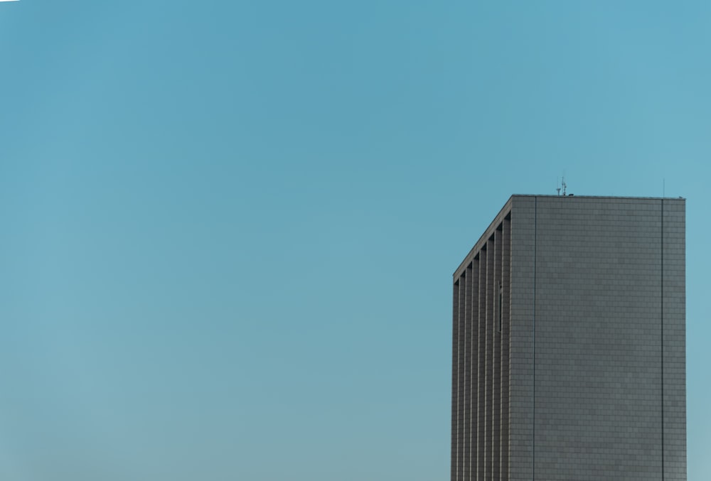 a plane flying in the sky over a tall building