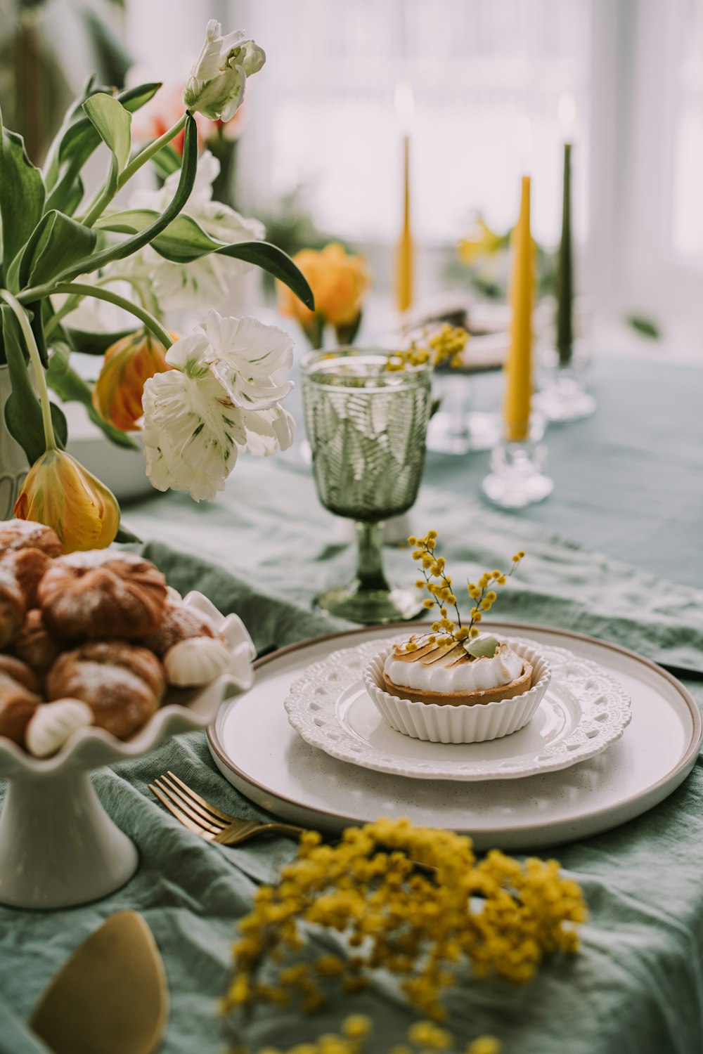 a table topped with a cupcake next to a vase of flowers