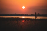 A vibrant sunset casting warm orange hues over a calm lake.