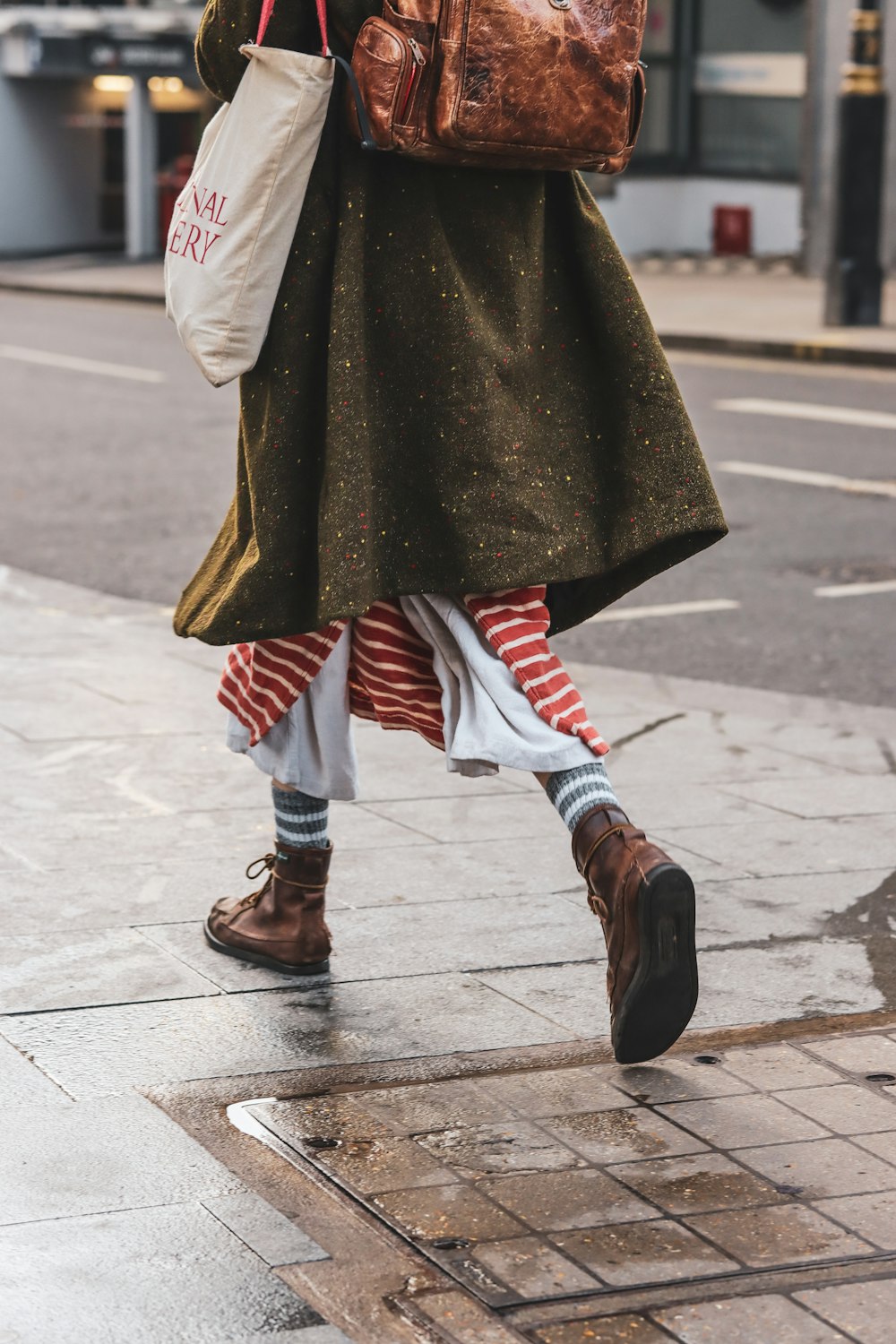 a woman walking down a street carrying a brown bag