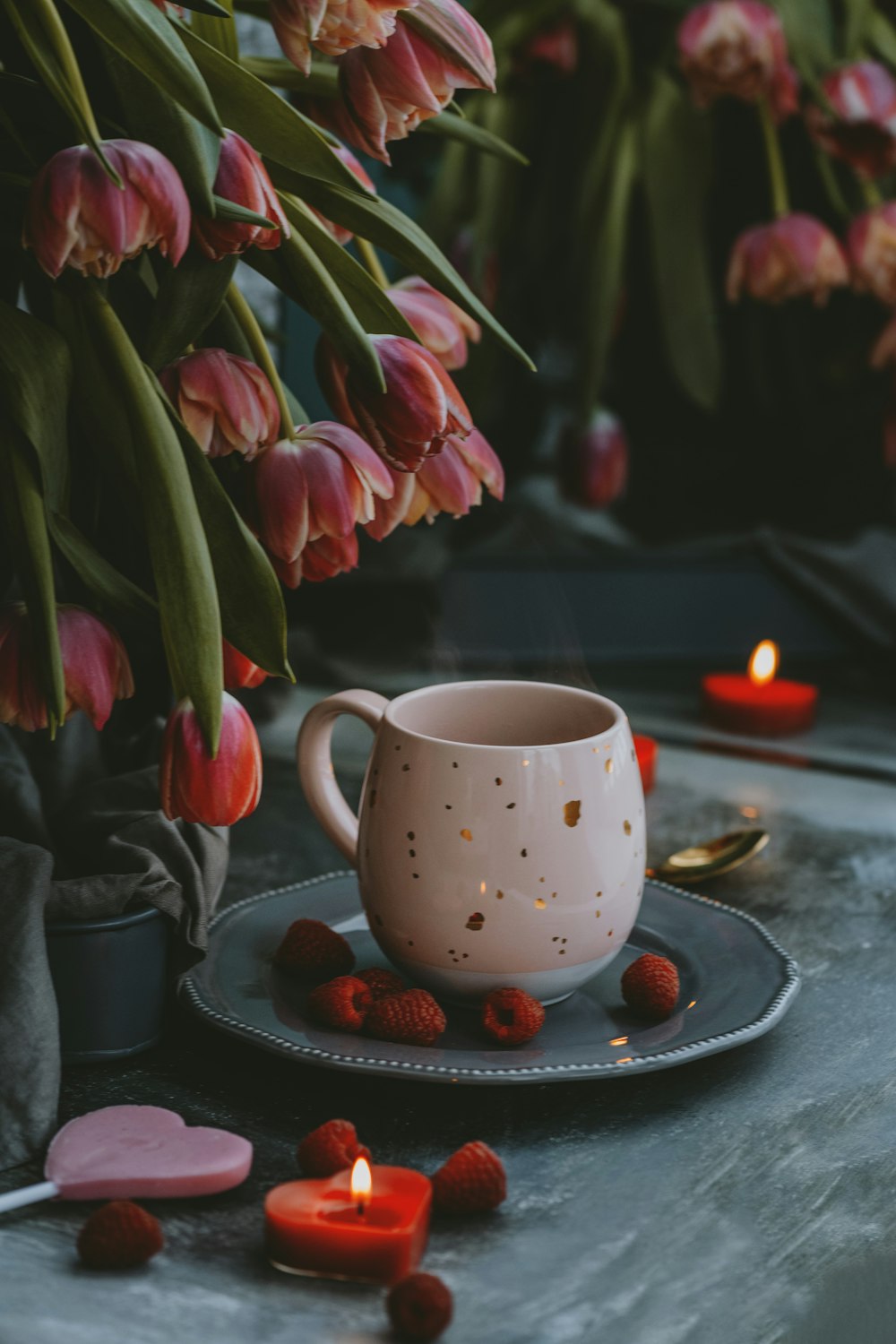 a cup of coffee on a plate next to some flowers