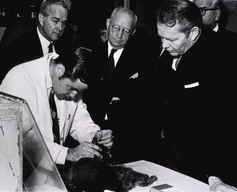 a group of men standing around a table