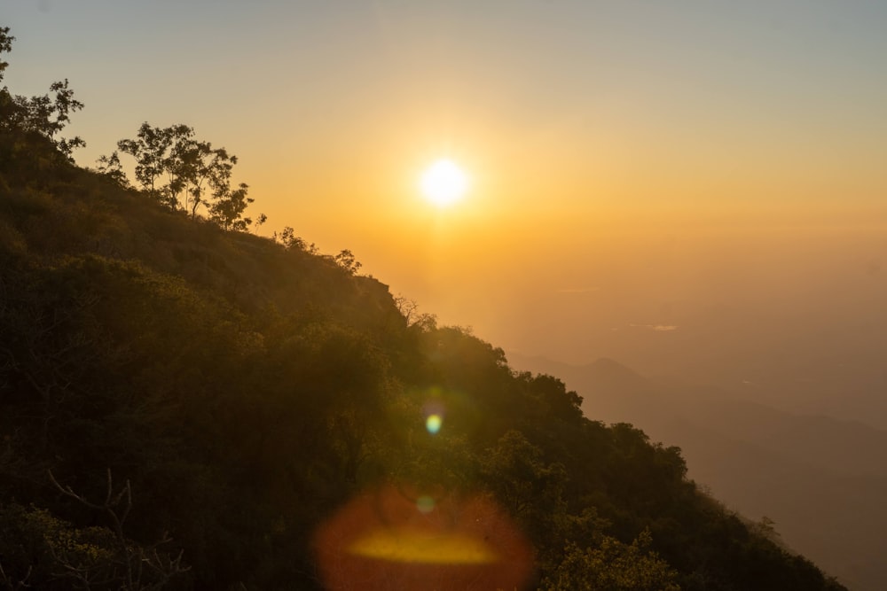 the sun is setting on a mountain side