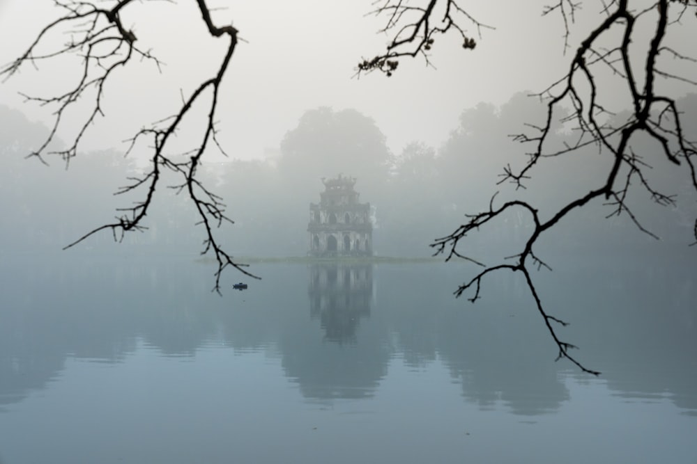 um corpo de água cercado por árvores e neblina