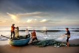 A group of local youth preparing fishing nets on a small boat at sunrise.
