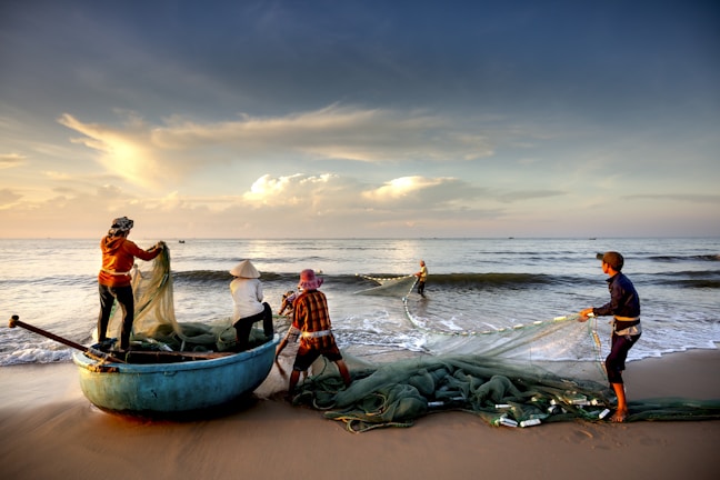 A group of local youth preparing fishing nets on a small boat at sunrise.