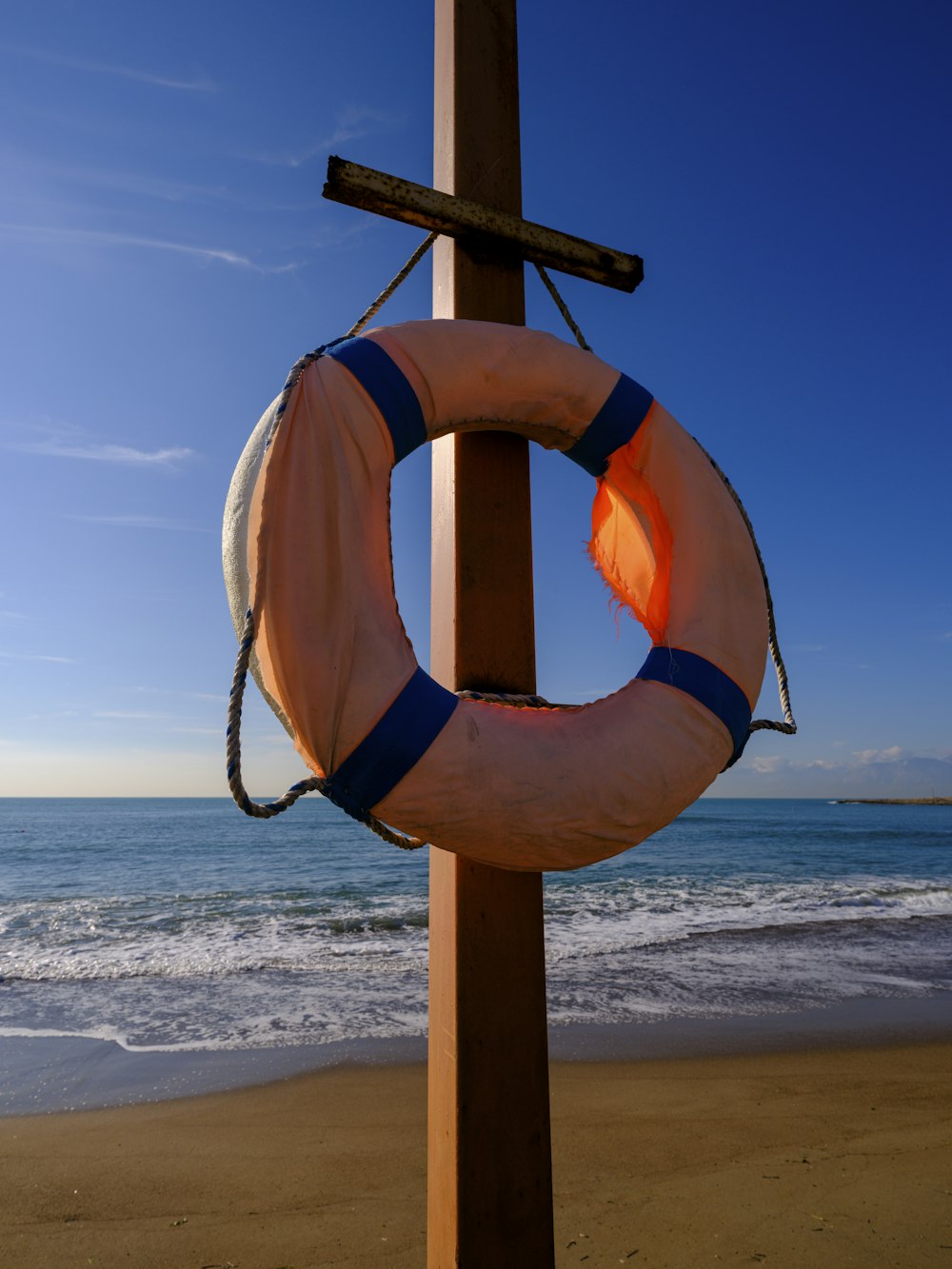 a life preserver hanging on a wooden pole on the beach