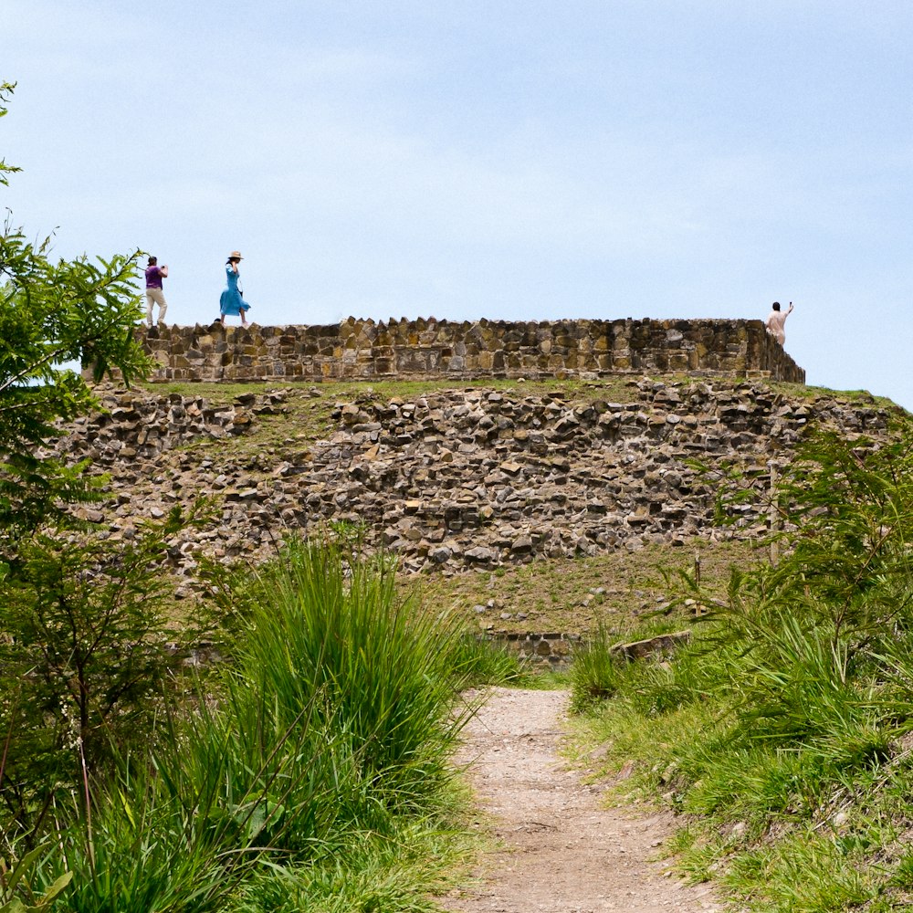 a couple of people standing on top of a stone wall