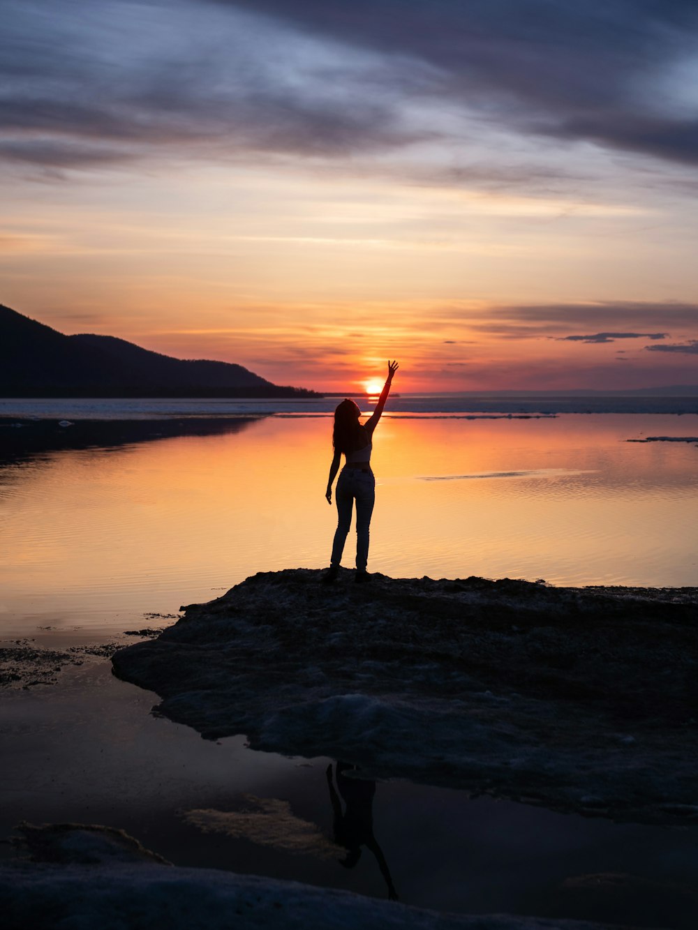 a person standing on a beach with their arms in the air