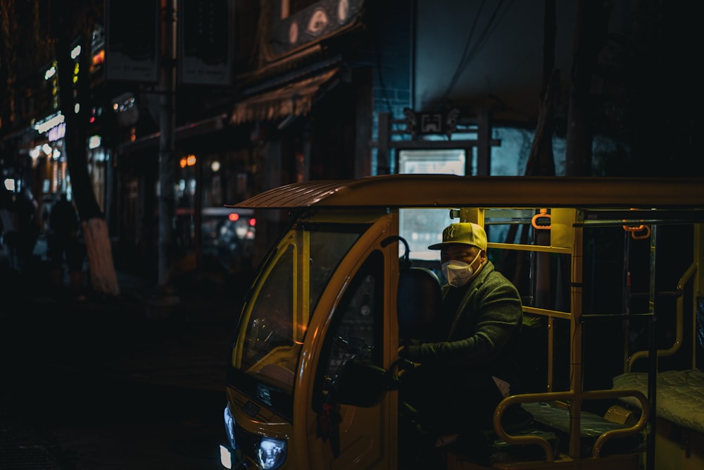 a man in a yellow hard hat driving a bus at night