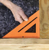 An artisan measuring and inspecting an outdoor garden project site with tools.