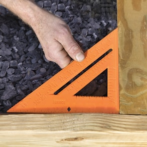 a person measuring a piece of wood with a ruler