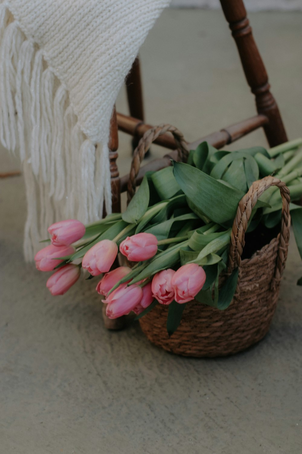 a basket of pink tulips sitting on the ground