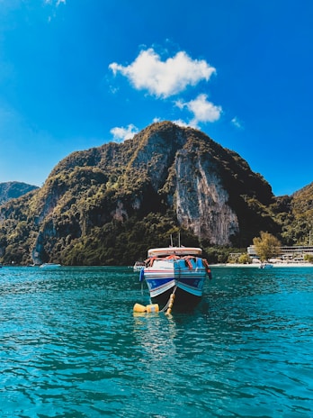 A colorful boat sailing near a tropical island with clear blue water and bright skies.