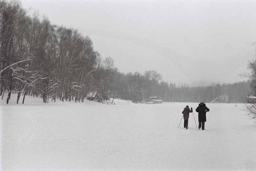 a couple of people riding skis across a snow covered field