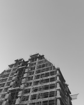 Photo of a modern building under construction with workers and scaffolding.