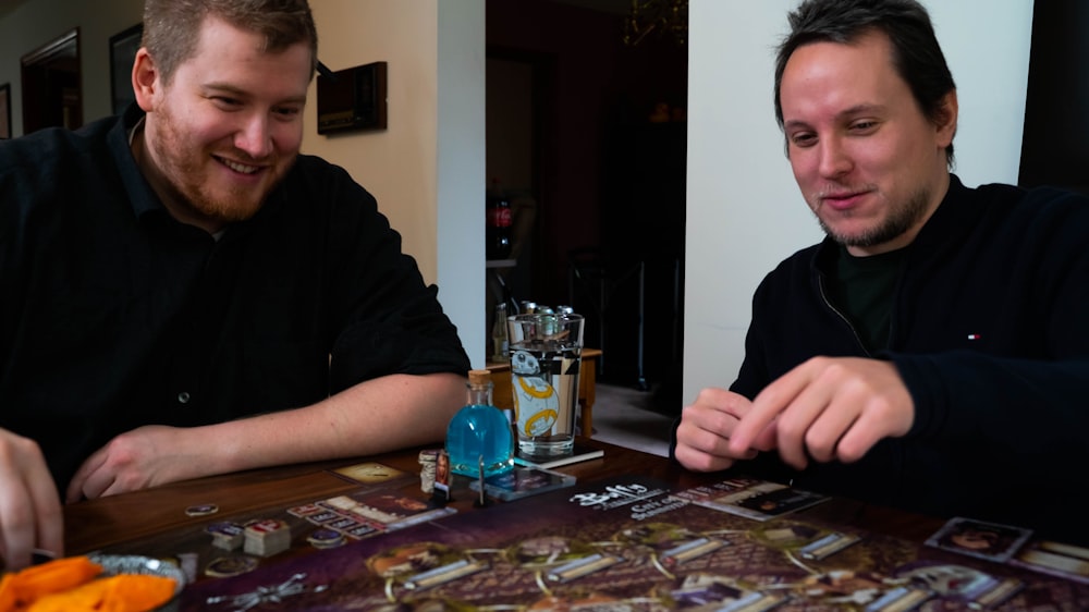 two men sitting at a table playing a board game