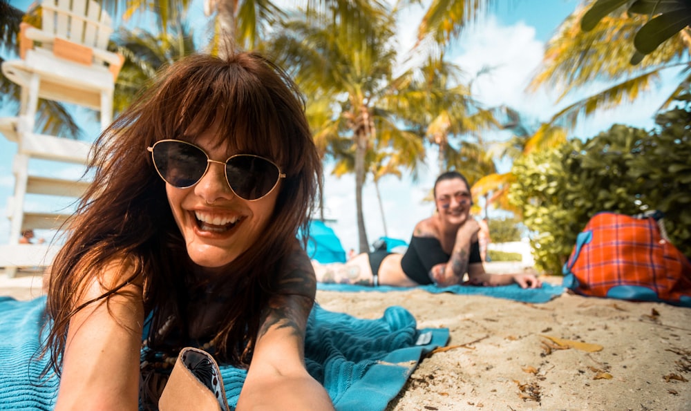 a woman laying on top of a blue towel on top of a beach