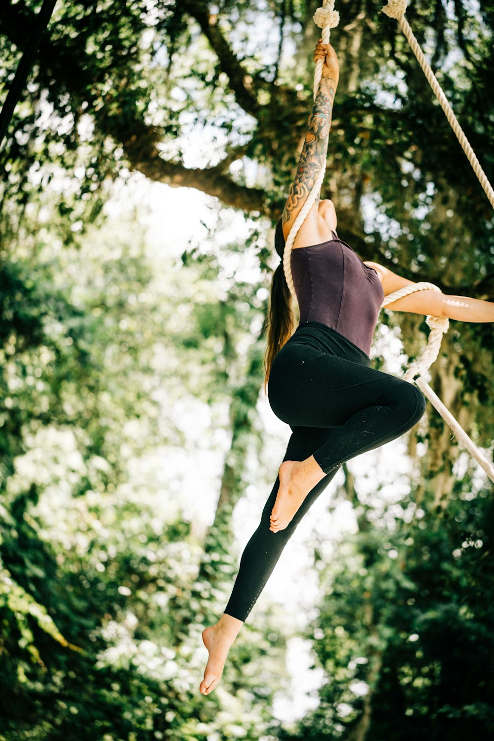 a woman hanging from a rope in a forest