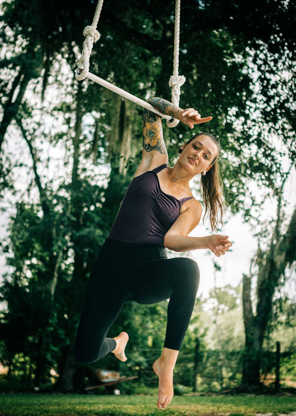 a woman swinging on a rope in a park