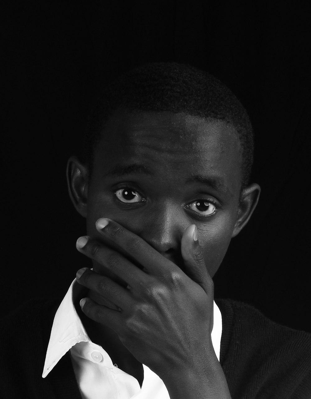 a black and white photo of a man covering his mouth