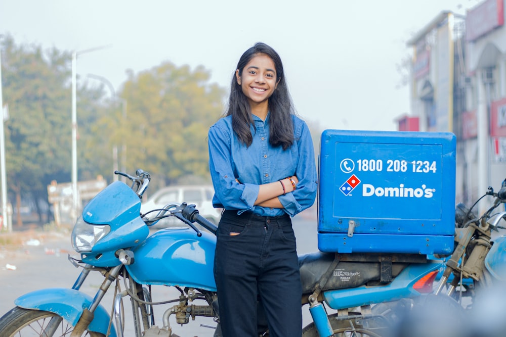 a woman standing next to a blue motorcycle