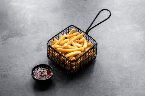 Elegant shot of golden french fries in a modern black bowl with soft shadows emphasizing texture.