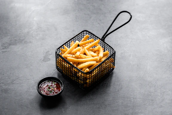 Elegant plated truffle fries with a side of dipping sauce on a sleek black slate.