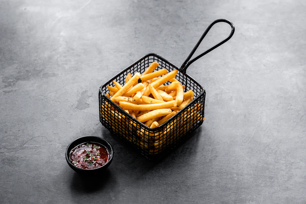 Crispy golden fries in a serving basket with dipping sauce.