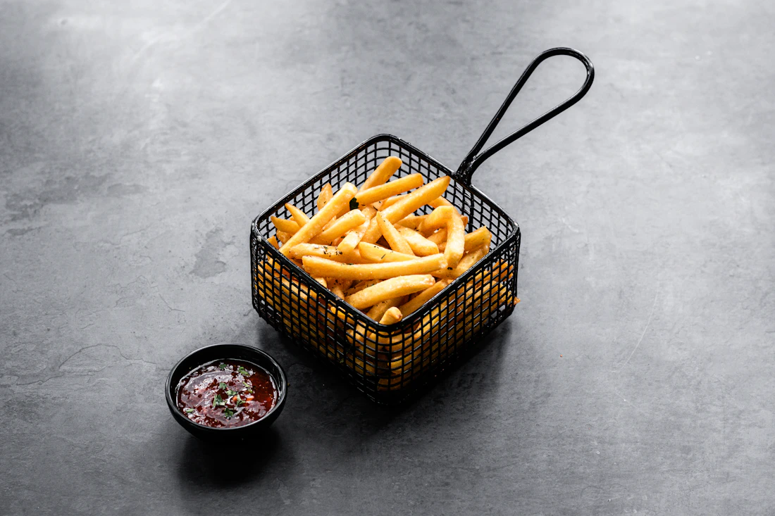 Crispy golden fries in a black serving basket with dipping sauce, used as a temporary category image.