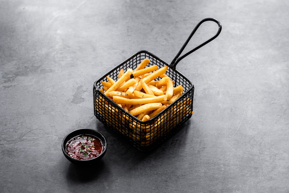 a basket filled with french fries next to a bowl of ketchup