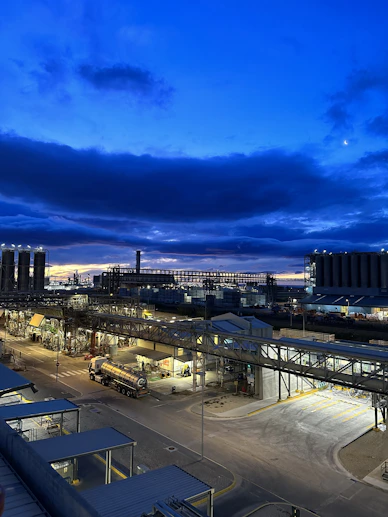 A panoramic view of a sprawling industrial complex under a deep navy sky, highlighting modern manufacturing and energy facilities.
