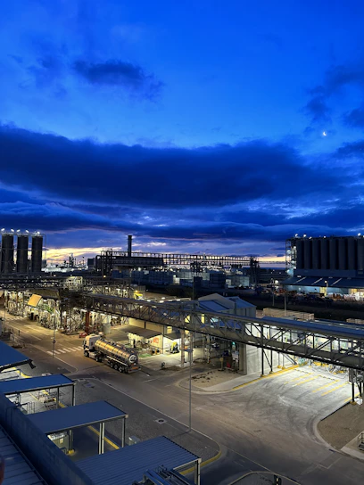 A panoramic view of a sprawling industrial complex under a deep navy sky, highlighting interconnected manufacturing and energy facilities.