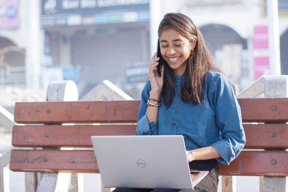 a woman sitting on a bench talking on a cell phone