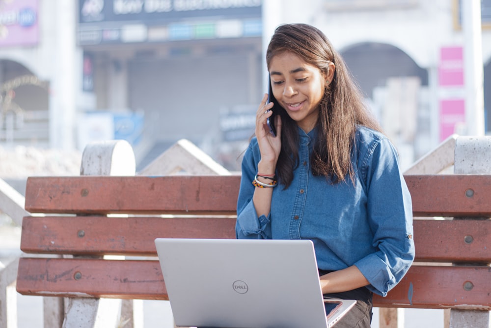 Una mujer sentada en un banco hablando por teléfono celular