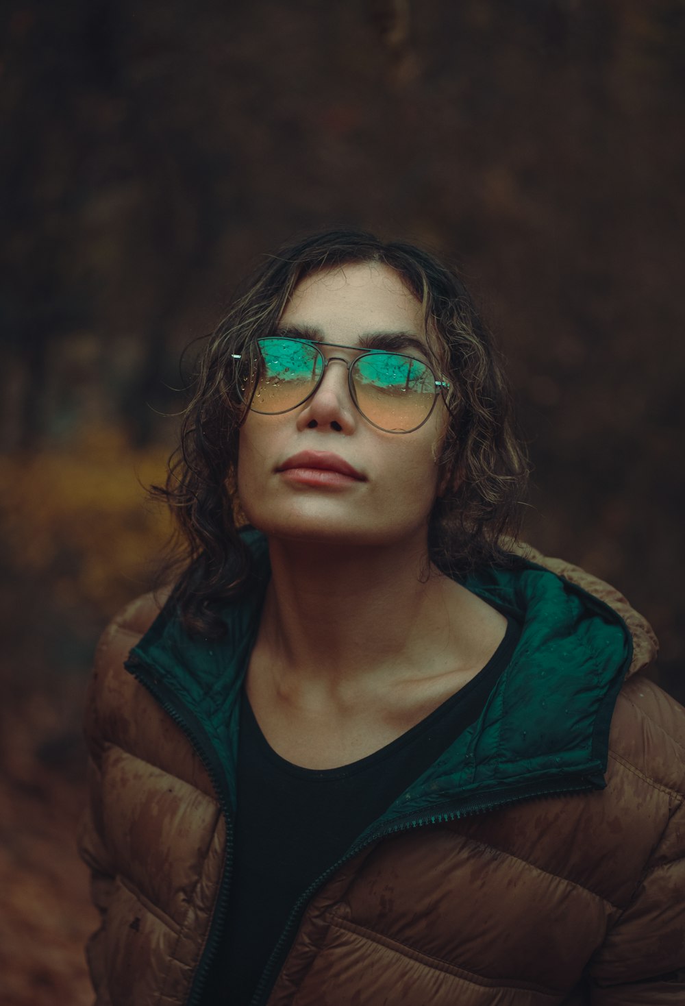 a woman wearing a brown jacket and green tinted glasses