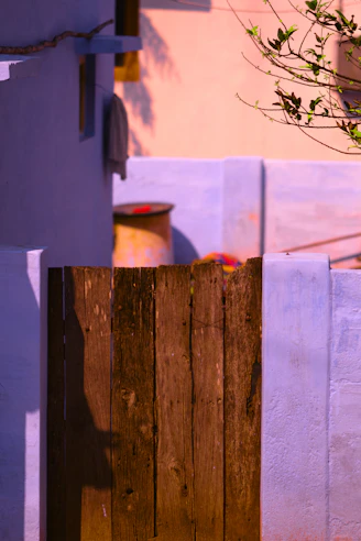 a wooden fence next to a building with a potted plant