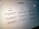 A close-up view of a computer screen displaying the ChatGPT interface. The screen is divided into three sections labeled 'Examples,' 'Capabilities,' and 'Limitations,' each containing text descriptions. The environment appears dimly lit, emphasizing the screen's brightness and focus.